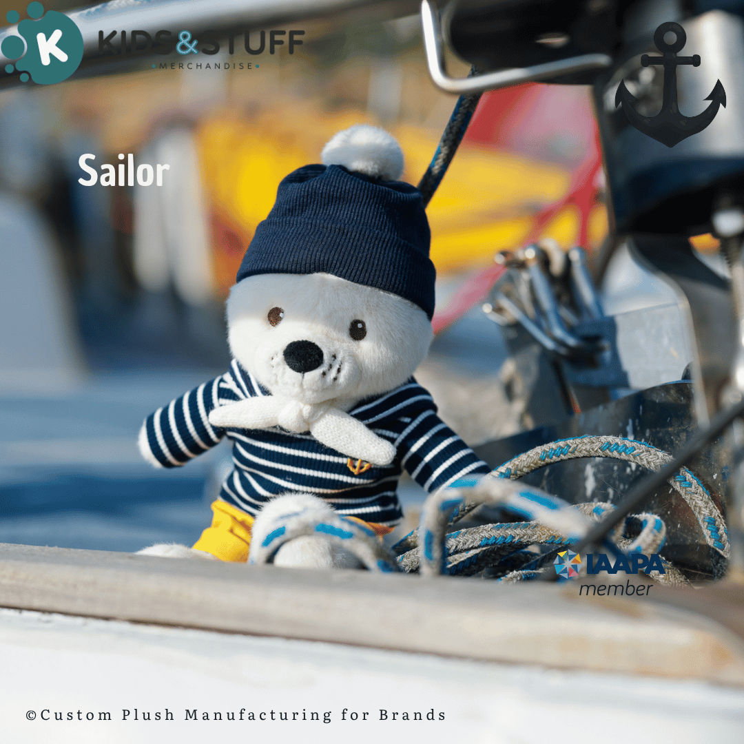 Sailor-themed teddy bear plush in navy striped shirt and hat sits on a boat with ropes
